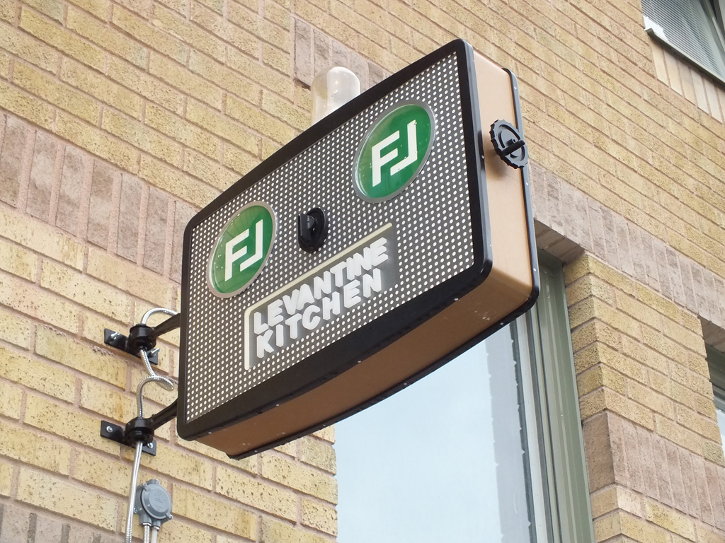 Skylt som sticker ut från vägg, text Levantine Kitchen