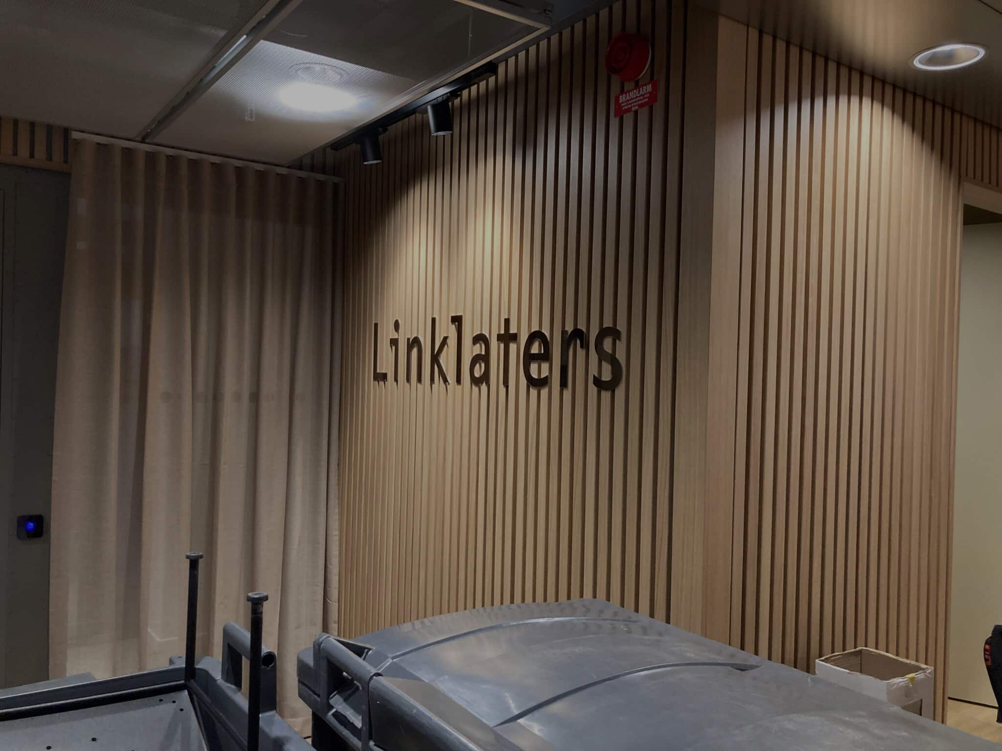 Mörklagd bild på vägg med Linklaters-logga