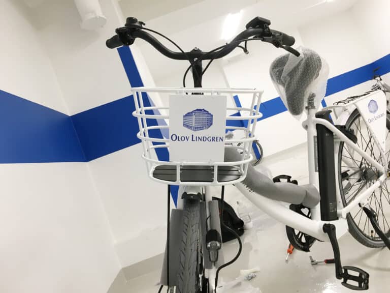 Vit cykel med logga på cykelkorgen: 